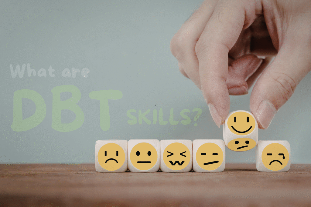 Hand holding small dice with different emotion faces, representing Dialectical Behavior Therapy (DBT) skills, with text reading “What are DBT skills?”